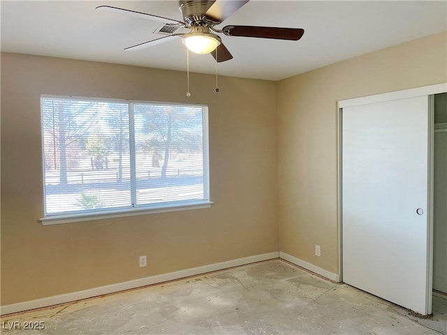 spare room with concrete flooring, ceiling fan, and baseboards