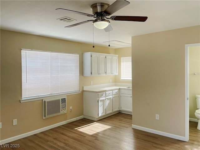 kitchen with white cabinets, baseboards, and wood finished floors