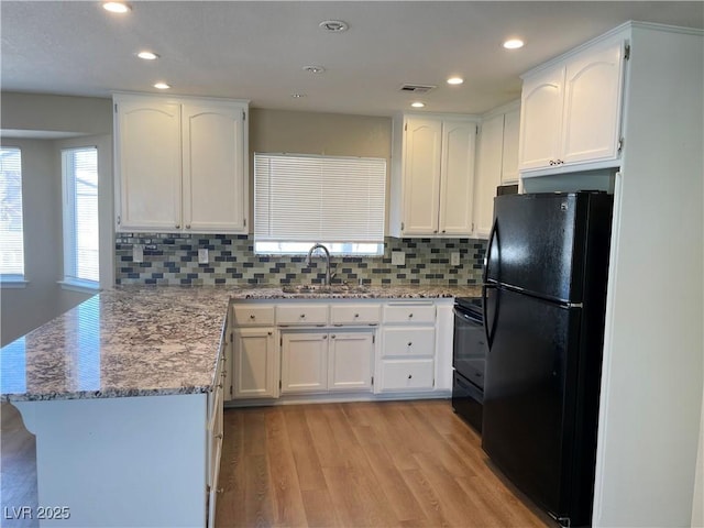 kitchen with visible vents, white cabinets, a sink, a peninsula, and black appliances