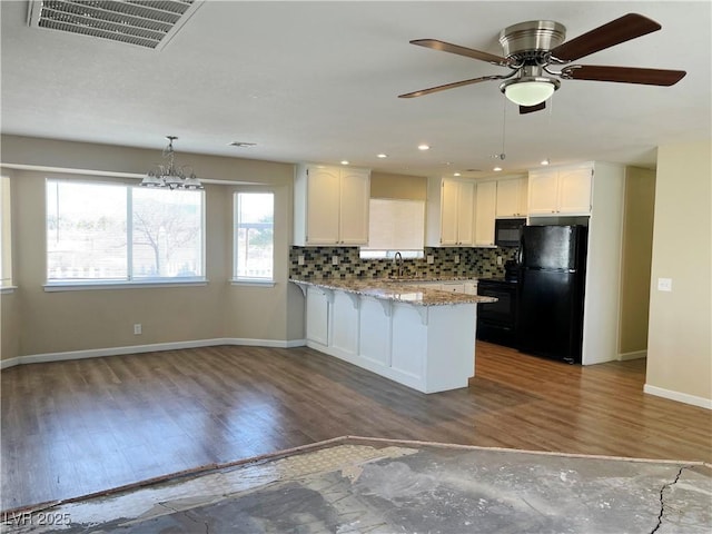 kitchen featuring visible vents, white cabinets, a peninsula, black appliances, and backsplash