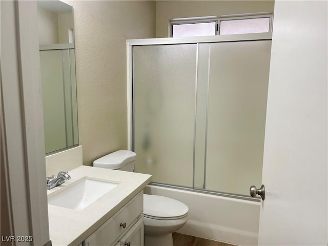 full bathroom with toilet, bath / shower combo with glass door, and vanity