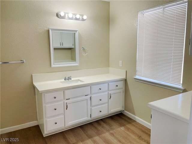 bathroom with wood finished floors, vanity, and baseboards