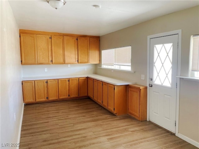 kitchen featuring light countertops, light wood-style flooring, and baseboards