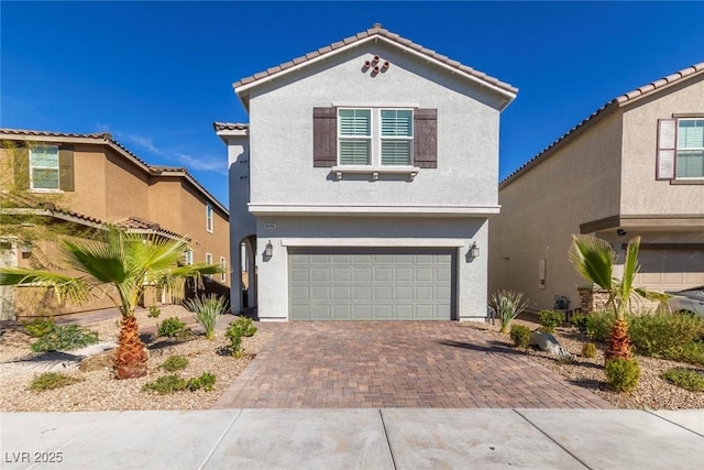 view of front of property featuring an attached garage, a tiled roof, decorative driveway, and stucco siding