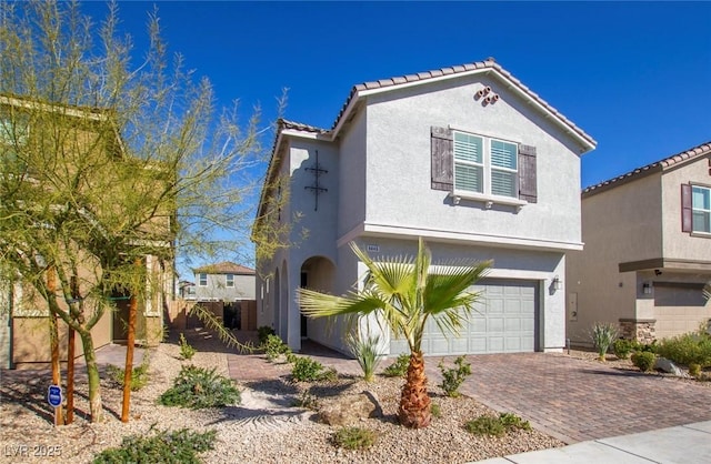 view of front facade featuring a garage, decorative driveway, a tile roof, and stucco siding