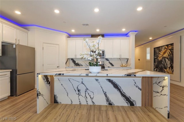 kitchen with a spacious island, visible vents, white cabinets, ornamental molding, and appliances with stainless steel finishes