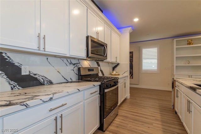 kitchen featuring white cabinets, light wood-style flooring, appliances with stainless steel finishes, light stone countertops, and open shelves