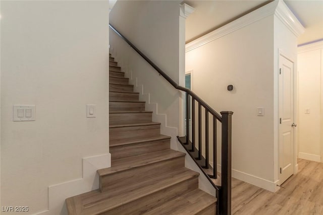 stairway with ornamental molding, wood finished floors, and baseboards