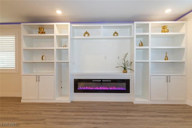 living area with light wood-type flooring, recessed lighting, and a glass covered fireplace