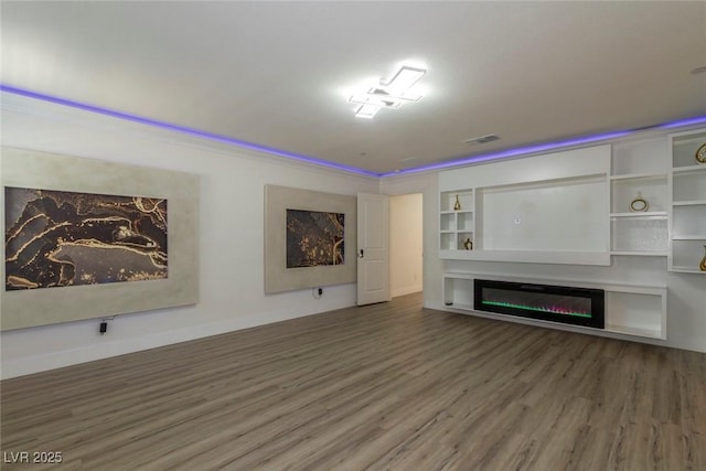 unfurnished living room with baseboards, visible vents, wood finished floors, and a glass covered fireplace