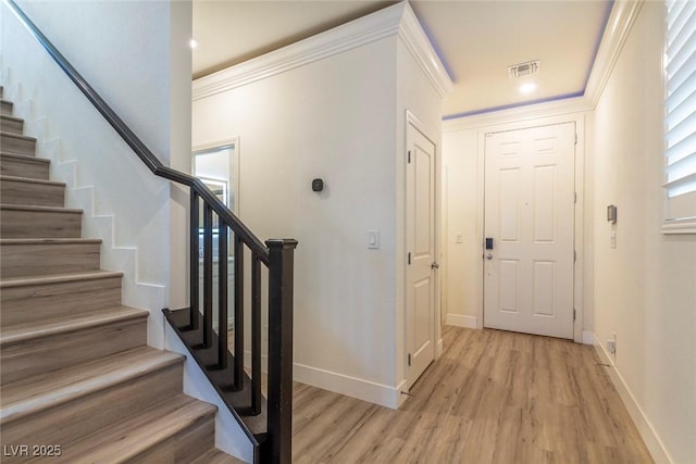 foyer entrance featuring visible vents, stairway, ornamental molding, light wood-type flooring, and baseboards