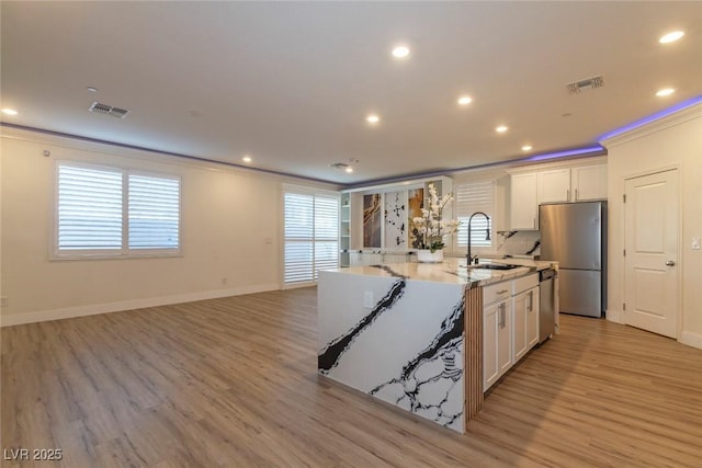 kitchen with stainless steel appliances, a sink, visible vents, white cabinets, and crown molding