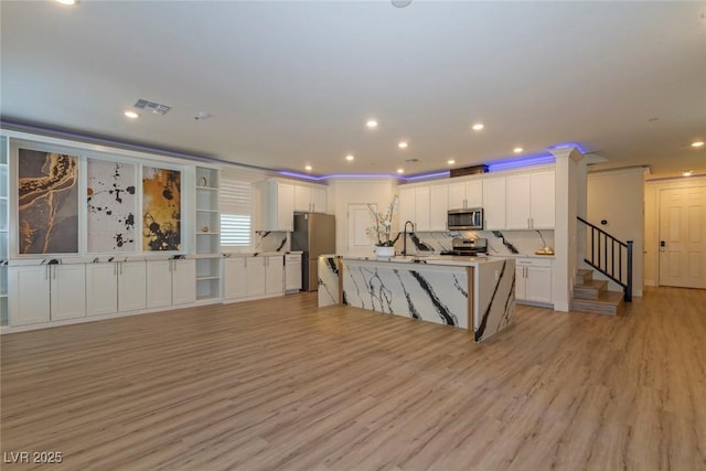 kitchen featuring appliances with stainless steel finishes, light wood-style flooring, visible vents, and white cabinets