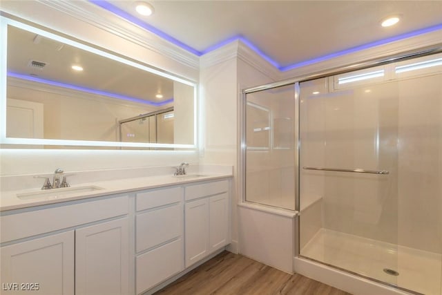 full bath featuring visible vents, wood finished floors, crown molding, a shower stall, and a sink