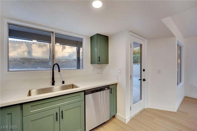 kitchen with green cabinetry, dishwasher, light wood-style flooring, light countertops, and a sink