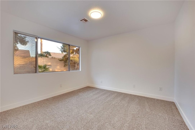 empty room featuring carpet floors, visible vents, and baseboards