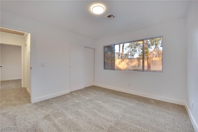 spare room featuring baseboards, visible vents, and light colored carpet