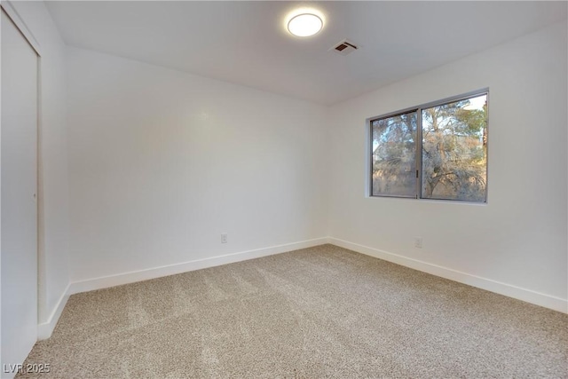 carpeted spare room featuring visible vents and baseboards