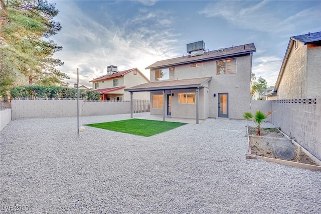 rear view of property with a patio, a fenced backyard, and a garden