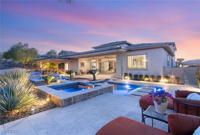 pool at dusk featuring a fenced in pool, a patio, a ceiling fan, fence, and an in ground hot tub