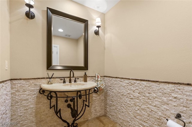 bathroom with visible vents, wainscoting, and tile walls