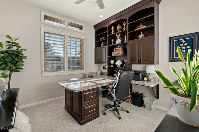 home office with a ceiling fan, light carpet, built in desk, and baseboards