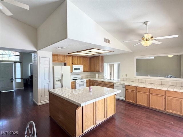 kitchen with tile counters, visible vents, a ceiling fan, a sink, and white appliances