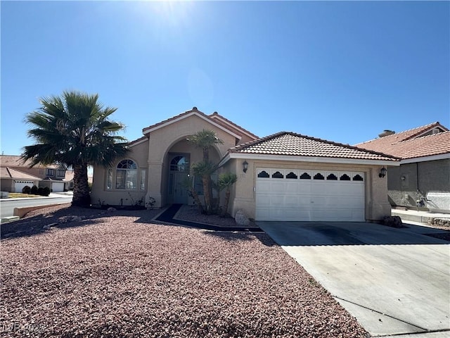 view of front of property featuring a garage, concrete driveway, a tile roof, and stucco siding