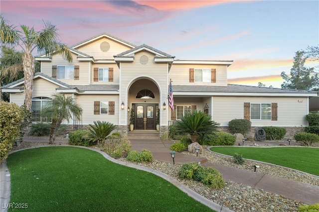 view of front of house featuring french doors and a lawn