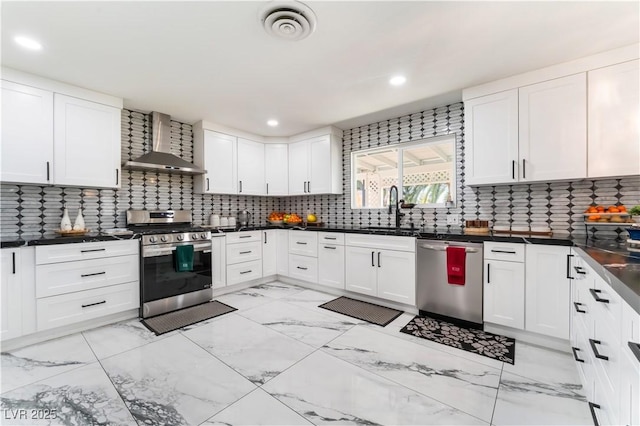 kitchen with stainless steel appliances, a sink, visible vents, white cabinets, and wall chimney exhaust hood