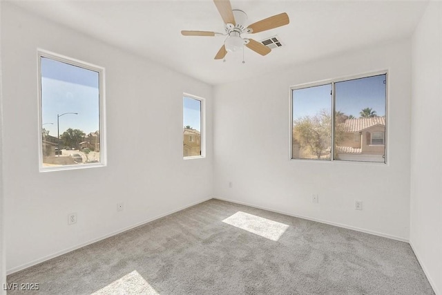 carpeted empty room featuring visible vents, a healthy amount of sunlight, baseboards, and ceiling fan