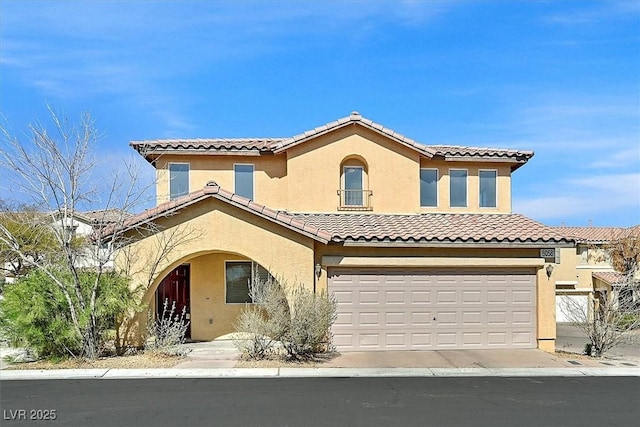 mediterranean / spanish-style house featuring stucco siding, an attached garage, and a tile roof