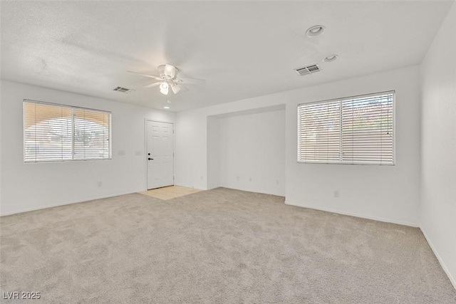 unfurnished room with carpet floors, visible vents, and a ceiling fan