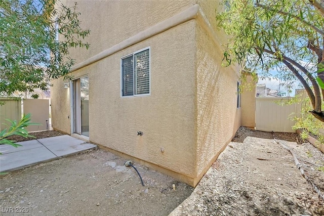 rear view of property with stucco siding, a patio, and a fenced backyard