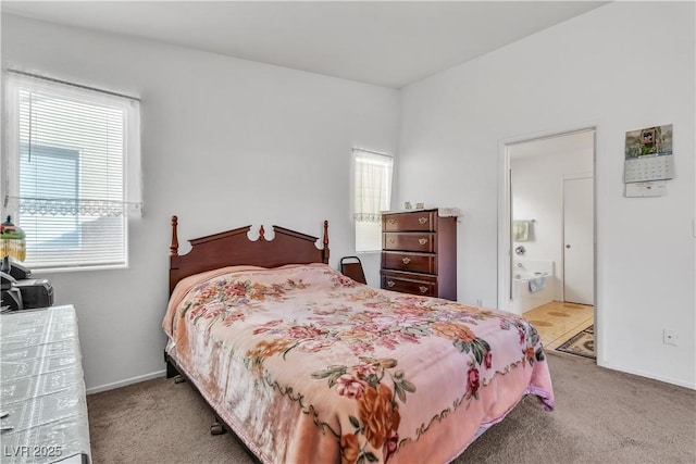 bedroom with ensuite bathroom, carpet, and baseboards