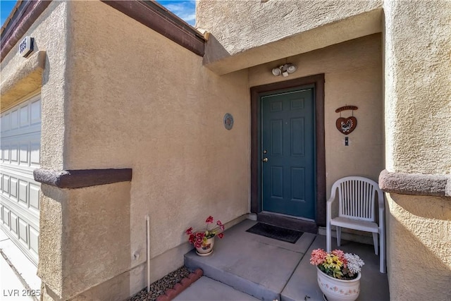 property entrance featuring a garage and stucco siding