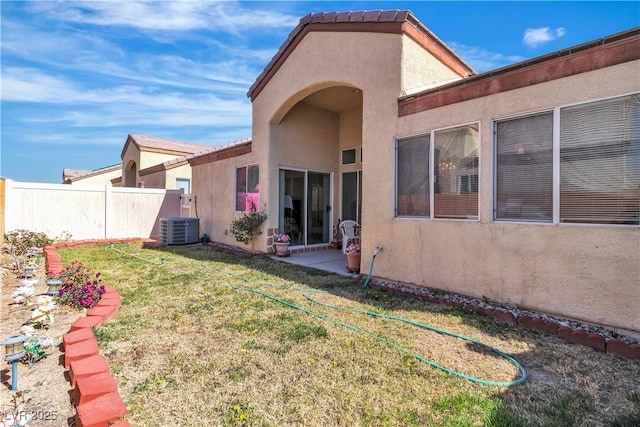 rear view of house featuring a tile roof, stucco siding, a lawn, fence, and cooling unit