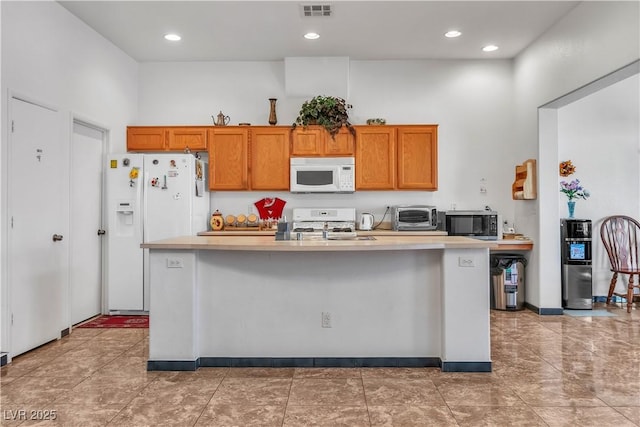 kitchen featuring light countertops, white appliances, brown cabinetry, and visible vents