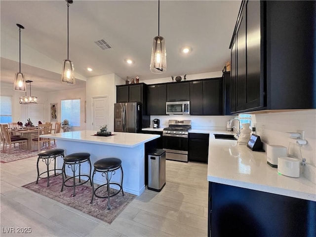 kitchen featuring dark cabinets, a sink, visible vents, appliances with stainless steel finishes, and a kitchen bar