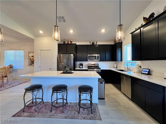 kitchen with stainless steel appliances, a kitchen bar, a sink, and dark cabinets