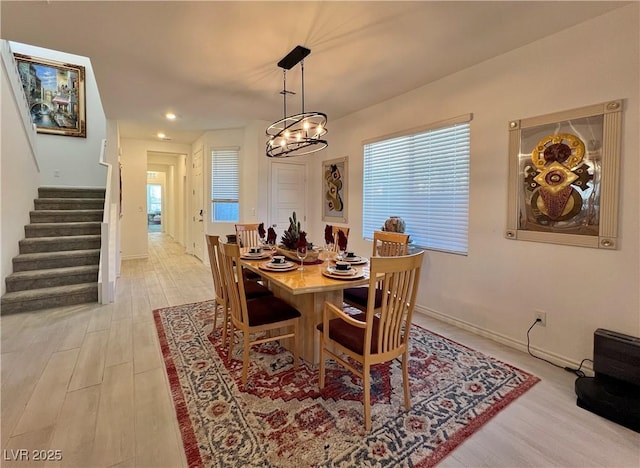 dining room featuring light wood finished floors, baseboards, stairway, and a wealth of natural light