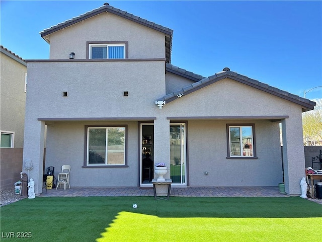 back of house with a yard, a tile roof, a patio, and stucco siding