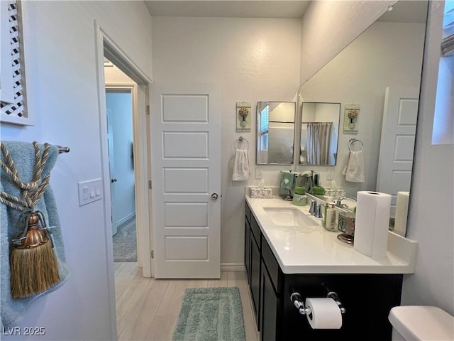 bathroom featuring toilet, wood finished floors, and vanity