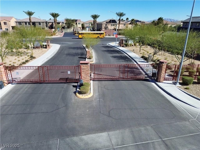 view of street with curbs, a gated entry, a gate, and a residential view