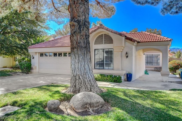 mediterranean / spanish home with a garage, concrete driveway, a tiled roof, and stucco siding