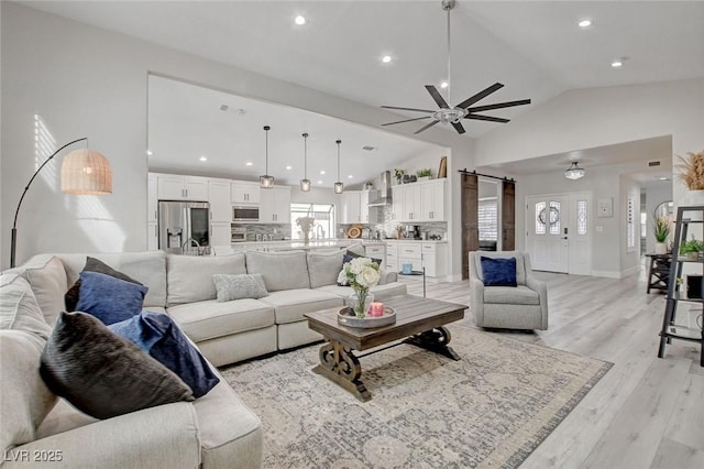 living area featuring baseboards, visible vents, a ceiling fan, vaulted ceiling, and light wood-style floors