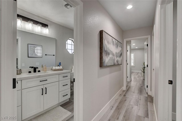 bathroom featuring plenty of natural light, baseboards, wood finished floors, and vanity