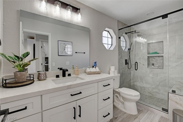 full bath with vanity, a marble finish shower, and toilet