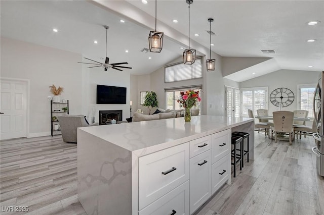 kitchen with a fireplace, a kitchen island, light wood-style flooring, and white cabinets