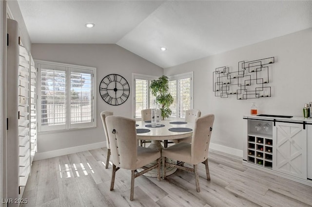 dining room featuring lofted ceiling, light wood-type flooring, baseboards, and recessed lighting